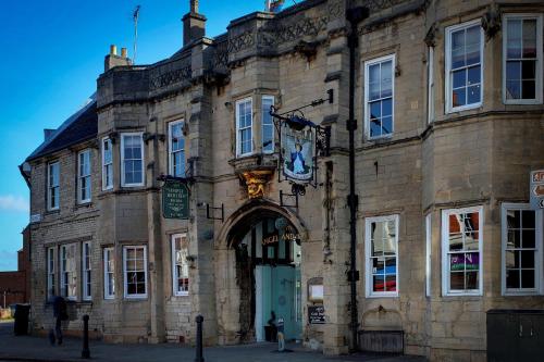 a large stone building with an archway on a street at Angel and Royal Hotel in Grantham