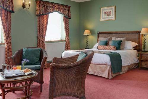 a hotel room with a bed and a table and chairs at Best Western Sysonby Knoll Hotel in Melton Mowbray