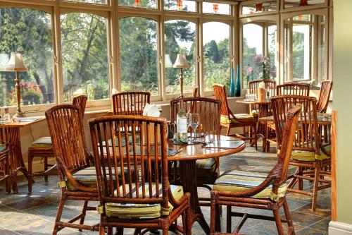 un restaurante con mesas y sillas de madera y ventanas en BEST WESTERN Sysonby Knoll en Melton Mowbray