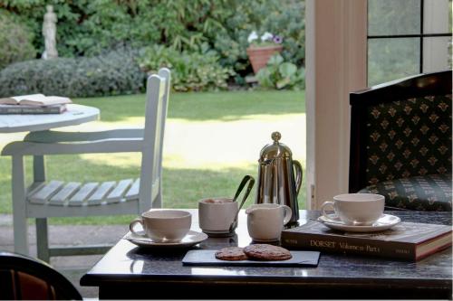 a table with coffee cups and a book on it at The Grange at Oborne in Sherborne