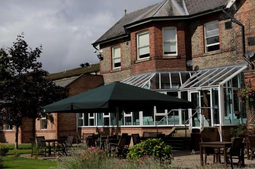 a building with tables and an umbrella in front of it at Burn Hall Hotel in Huby