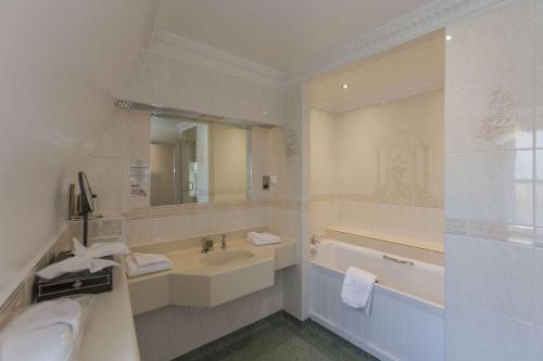 圣彼得港Best Western Moores Central Hotel的白色的浴室设有浴缸、水槽和浴缸。