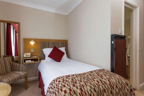 a hotel room with a bed and a chair at Best Western Moores Central Hotel in St Peter Port