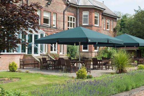 a patio with tables and umbrellas in front of a building at Burn Hall Hotel in Huby