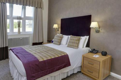 a hotel room with a large bed and two windows at Walworth Castle Hotel, BW Signature Collection in Darlington