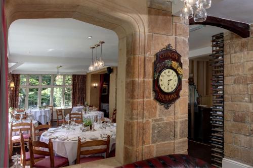 a clock on the wall of a restaurant with tables at The Grange at Oborne in Sherborne