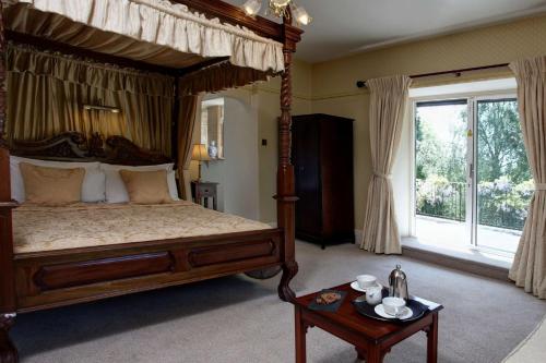 a bedroom with a canopy bed and a table at The Grange at Oborne in Sherborne