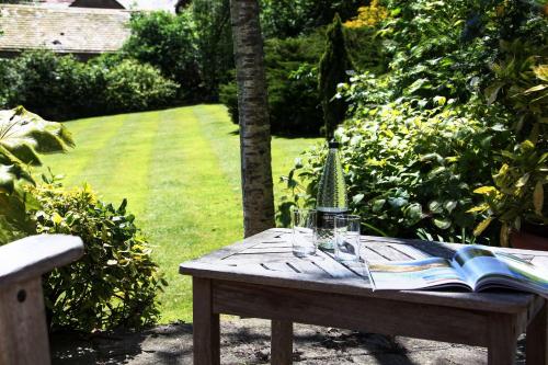 a wooden table with a book and glasses on it at The Grange at Oborne in Sherborne