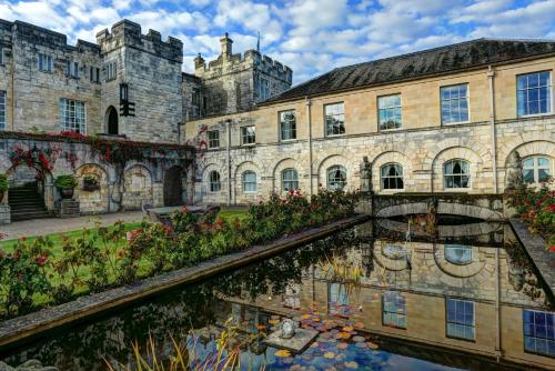 an old building and a canal in front of a building at Hazlewood Castle & Spa in Tadcaster