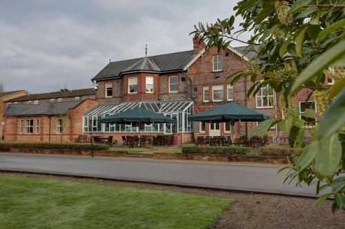 a building with tables and umbrellas in front of it at Burn Hall Hotel in Huby