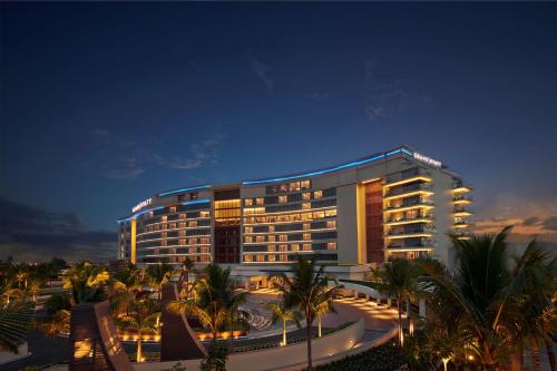 a hotel building with palm trees at night at Grand Hyatt Kochi Bolgatty in Cochin