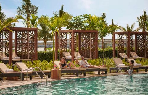 a group of people sitting around a pool at a resort at Grand Hyatt Kochi Bolgatty in Cochin
