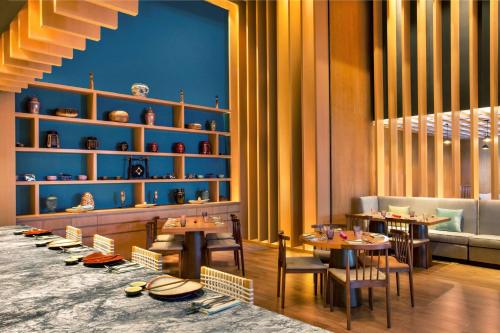 a restaurant with tables and chairs and shelves with vases at Grand Hyatt Kochi Bolgatty in Cochin