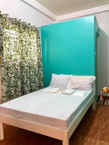 a bedroom with a bed with a blue headboard at Michelina Princess Guest House in Loboc