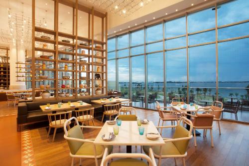 a restaurant with tables and chairs and large windows at Grand Hyatt Kochi Bolgatty in Cochin