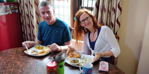 a man and a woman sitting at a table eating food at Panauti Homestay in Panauti