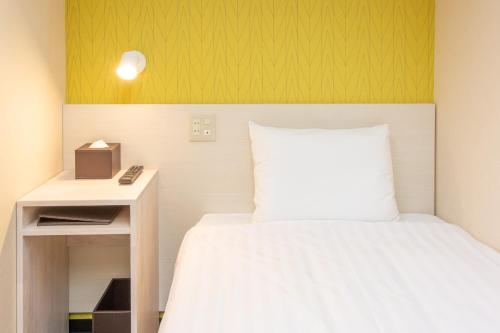 a small bedroom with a bed and a night stand at Kuretake Inn Gotemba Inter Gold Cabin in Gotemba