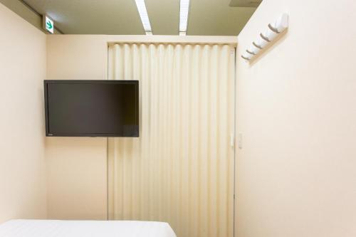 a flat screen tv on a wall next to a curtain at Kuretake Inn Gotemba Inter Gold Cabin in Gotemba