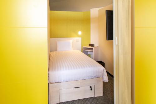 a small bedroom with a bed in a yellow room at Kuretake Inn Gotemba Inter Gold Cabin in Gotemba