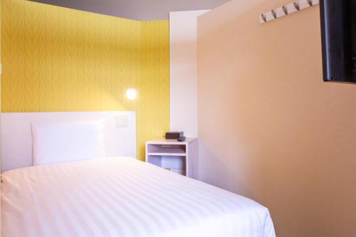 a bedroom with a white bed and a yellow wall at Kuretake Inn Gotemba Inter Gold Cabin in Gotemba