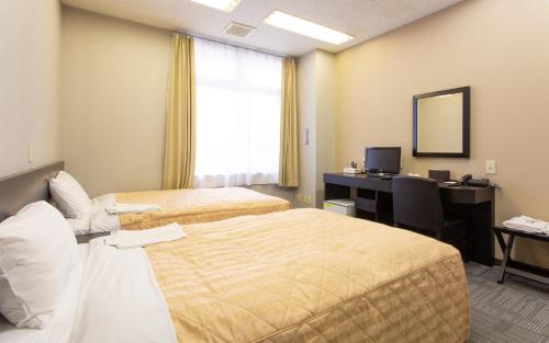 a hotel room with two beds and a desk at Kuretake Inn Gotemba Inter Gold Cabin in Gotemba