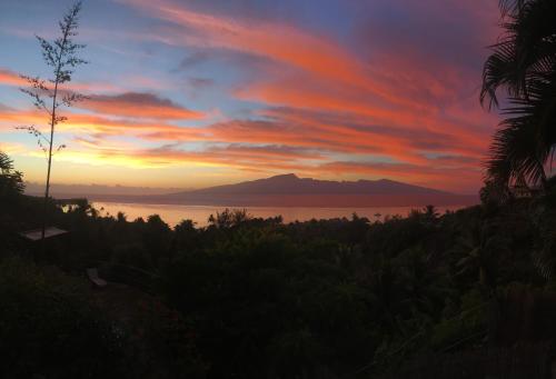 a sunset over the ocean with a mountain in the background at Moorea Happy Bungalow in Teavaro