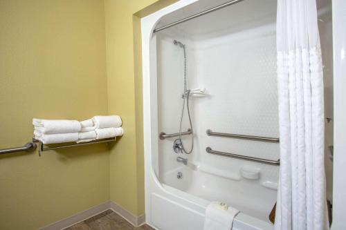 y baño con bañera, ducha y toallas. en Travelodge by Wyndham Gardiner Yellowstone Park North Entr, en Gardiner