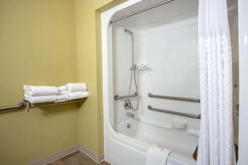 a bathroom with a tub and a shower with towels at Travelodge by Wyndham Gardiner Yellowstone Park North Entr in Gardiner