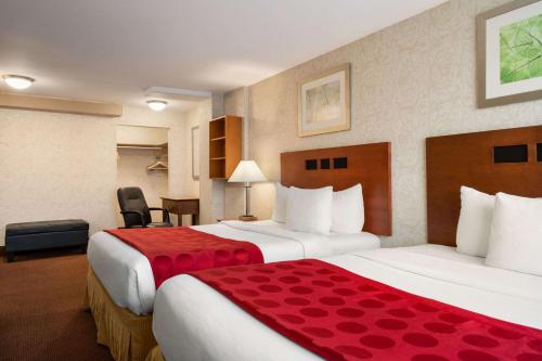 a hotel room with two beds with red sheets at Ramada Plaza by Wyndham Montreal in Montréal