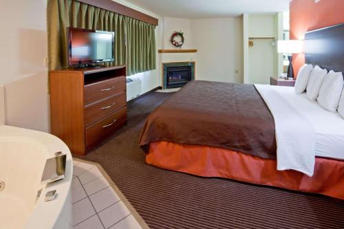 a hotel room with a bed and a flat screen tv at AmericInn by Wyndham Coon Rapids in Coon Rapids