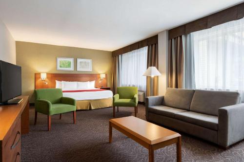 a hotel room with a bed and a couch and chairs at Ramada Plaza by Wyndham Montreal in Montréal