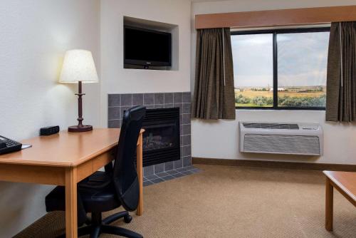 a hotel room with a desk and a fireplace at AmericInn by Wyndham Belle Fourche in Belle Fourche