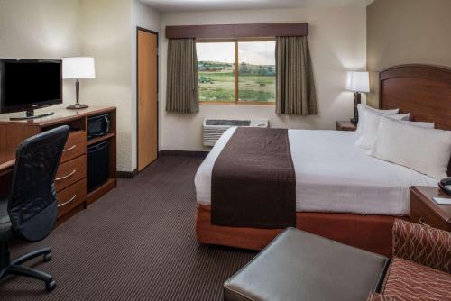a hotel room with a bed and a desk and a television at AmericInn by Wyndham Belle Fourche in Belle Fourche
