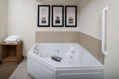 a white tub in a bathroom with three pictures on the wall at AmericInn by Wyndham Belle Fourche in Belle Fourche