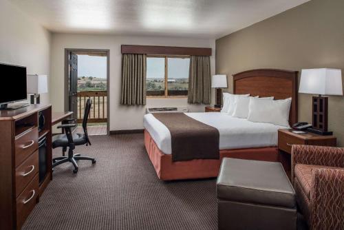 a hotel room with a bed and a desk and a television at AmericInn by Wyndham Belle Fourche in Belle Fourche
