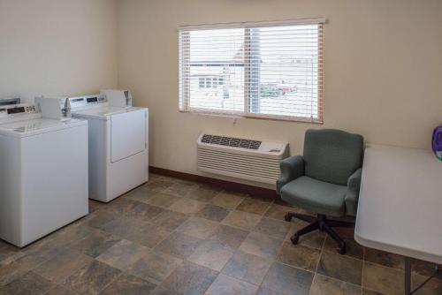 a room with a refrigerator and a chair and a window at AmericInn by Wyndham Belle Fourche in Belle Fourche