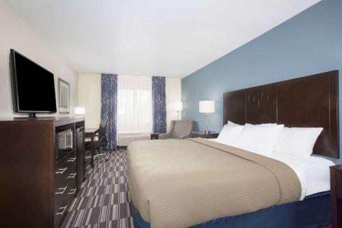 a hotel room with a large bed and a flat screen tv at AmericInn by Wyndham Mount Pleasant in Mount Pleasant