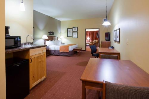 a hotel room with a bed and a dining room at AmericInn by Wyndham Fargo Medical Center in Fargo