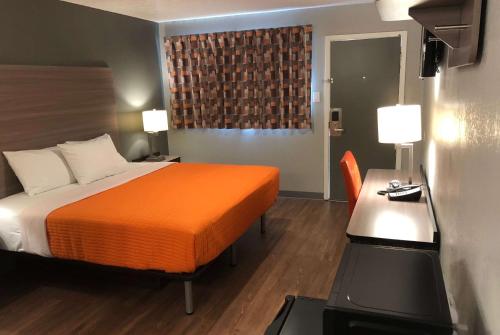 a hotel room with a bed and a desk and a television at Super 8 by Wyndham Sonora in Sonora