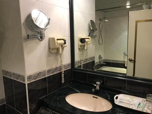 a bathroom with a sink and a mirror at Sunrise Hotel in Tainan