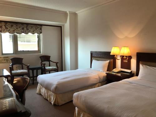a hotel room with two beds and a table and chairs at Sunrise Hotel in Tainan