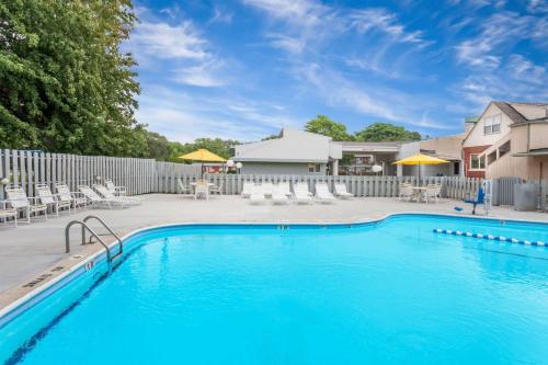 a swimming pool in a yard with chairs and a fence at Super 8 by Wyndham Stevensville St Joseph in Stevensville