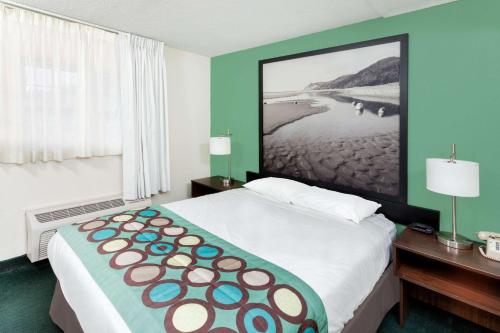 a hotel room with a bed with a large picture on the wall at Super 8 by Wyndham Stevensville St Joseph in Stevensville