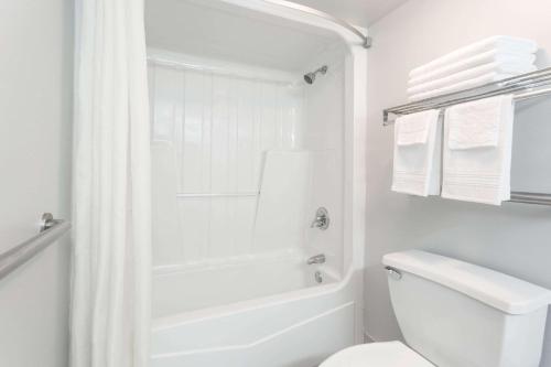 a white bathroom with a shower and a toilet at Super 8 by Wyndham Adel GA I-75 in Adel