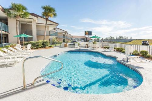 a swimming pool with lounge chairs and a resort at Super 8 by Wyndham Adel GA I-75 in Adel