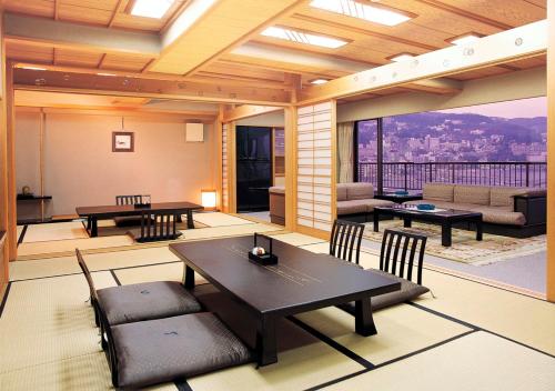 a living room with tables and chairs and a balcony at Uomisaki Hotel in Atami