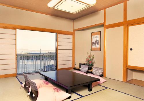 a room with a table and chairs and a balcony at Uomisaki Hotel in Atami