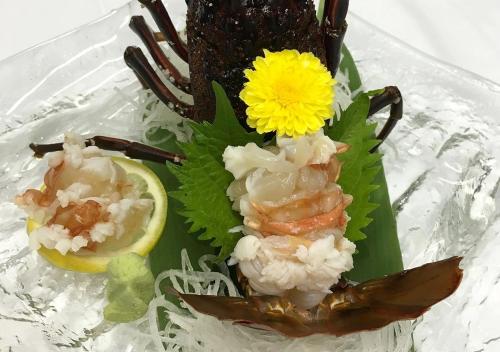 a plate of sushi with shrimp and a yellow flower at Uomisaki Hotel in Atami
