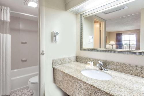 a bathroom with a sink and a mirror and a toilet at Days Inn by Wyndham Camp Springs Andrews AFB in Camp Springs