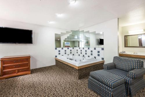 a bathroom with a tub and a chair and a tv at Super 8 by Wyndham Pittsburgh/Monroeville in Monroeville
